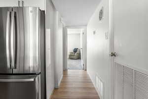Corridor with light wood-type flooring and baseboards