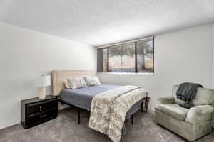 Carpeted bedroom featuring a textured ceiling and baseboards