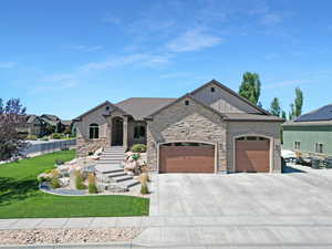 View of front facade featuring an attached garage, board and batten siding, stone siding, and driveway