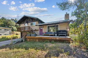 View of front of property with a deck, an attached garage, a chimney, brick siding, and a metal roof