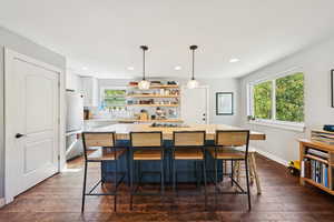 Kitchen featuring open shelves, pendant lighting, a center island, white cabinets, and dark wood finished floors