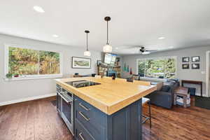 Kitchen with a kitchen breakfast bar, butcher block counters, open floor plan, hanging light fixtures, and recessed lighting