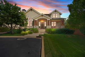 Craftsman-style home featuring stone siding, a porch, and a lawn