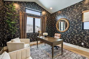Office area with wallpapered walls, wood finished floors, and vaulted ceiling