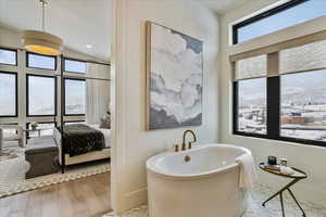 Bathroom with a freestanding tub, ensuite bathroom, wood finished floors, vaulted ceiling, and recessed lighting