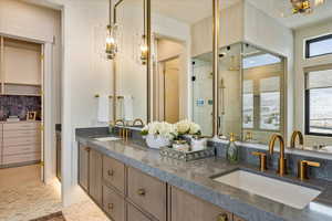 Full bathroom featuring a chandelier, double vanity, a stall shower, tasteful backsplash, and a closet