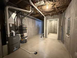 Unfinished below grade area with water heater, electric panel, and heating unit