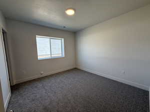 Empty room with carpet floors and a textured ceiling