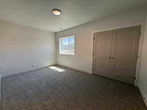 Unfurnished bedroom featuring carpet flooring, a textured ceiling, and a closet