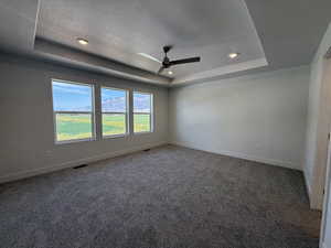 Empty room with a tray ceiling, carpet, a textured ceiling, ceiling fan, and recessed lighting