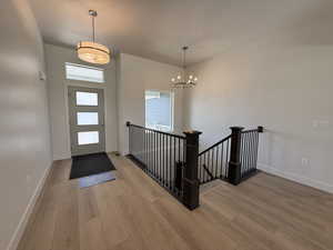 Entrance foyer with light wood finished floors and a chandelier