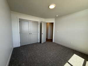 Unfurnished bedroom with carpet flooring, a closet, and a textured ceiling