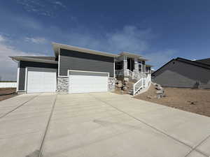 View of front of house with stone siding, a garage, and driveway