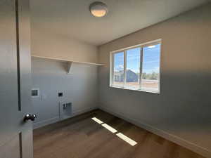Laundry area with dark wood finished floors, washer hookup, and hookup for an electric dryer