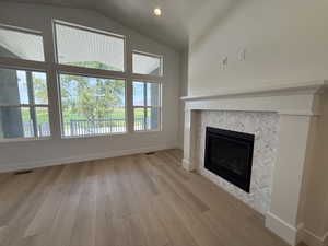 Unfurnished living room with a tile fireplace, vaulted ceiling, light wood-style floors, and recessed lighting