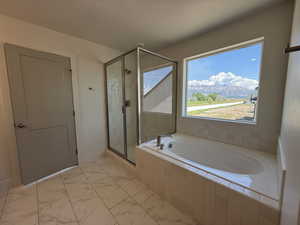 Bathroom featuring a shower stall, a bath, and light marble finish flooring