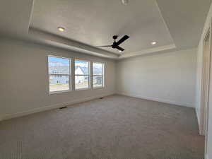 Carpeted Primary room featuring a tray ceiling, a textured ceiling, a ceiling fan, and recessed lighting