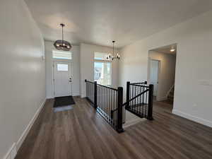 Entryway with a chandelier, dark wood-type flooring, and stairway