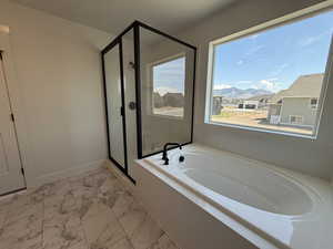 Bathroom with a mountain view, a stall shower, a garden tub, and light marble finish flooring