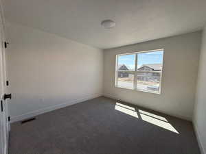 Spare room featuring carpet flooring and baseboards