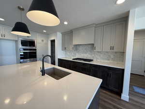 Kitchen with recessed lighting, decorative backsplash, stainless steel appliances, dark wood-type flooring, and light stone counters