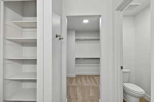 Bathroom with a spacious closet and light carpet