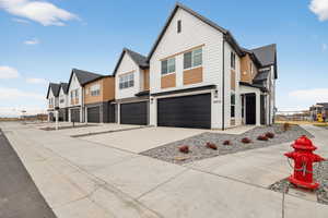 View of front of house featuring a residential view, a garage, concrete driveway, and a shingled roof
