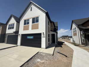 View of front of property with a garage, concrete driveway, and a residential view