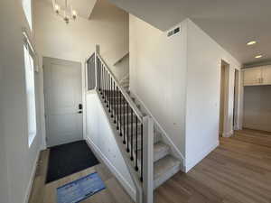 Stairs with wood finished floors, recessed lighting, and a chandelier
