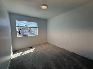 Empty room with carpet floors and a textured ceiling