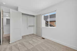 Unfurnished bedroom with light carpet and a closet