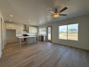 Kitchen with a kitchen island, plenty of natural light, wall chimney exhaust hood, appliances with stainless steel finishes, and recessed lighting