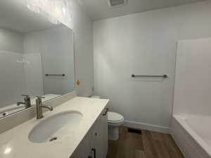 Full bath with dark wood-type flooring, vanity, and shower / washtub combination