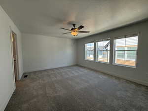 Carpeted spare room featuring a textured ceiling and a ceiling fan