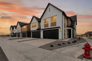 View of front facade featuring an attached garage, concrete driveway, and a residential view