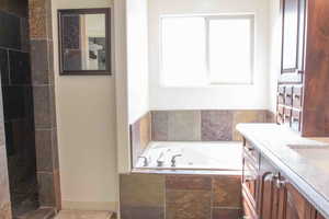 Bathroom featuring a walk in shower, a tub with jets, and double vanity