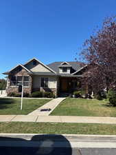 View of front of home featuring a front yard, stone siding, and stucco siding