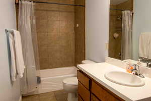 Full bathroom with shower / bath combo with shower curtain, light tile patterned floors, and vanity