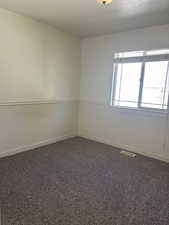 Unfurnished room with baseboards and dark colored carpet