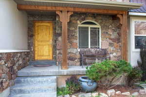 View of exterior entry featuring stone siding and covered porch