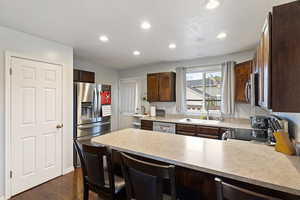 Kitchen featuring a peninsula, appliances with stainless steel finishes, dark wood finished floors, recessed lighting, and a breakfast bar area