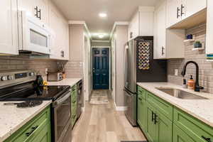 Kitchen with decorative backsplash, appliances with stainless steel finishes, light stone countertops, ornamental molding, and recessed lighting