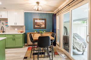 Dining area with light wood-style floors, a chandelier, and crown molding