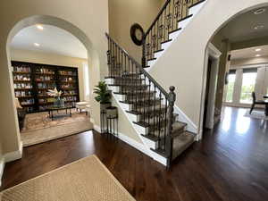 Entryway with arched walkways, recessed lighting, dark wood finished floors, and stairway