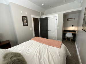 Bedroom with carpet flooring, lofted ceiling, a closet, and a desk