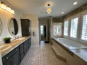 Full bathroom featuring healthy amount of natural light, a stall shower, double vanity, a bath, and recessed lighting