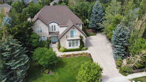French provincial home featuring stone siding, roof with shingles, a front lawn, and stucco siding
