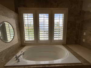 Full bathroom featuring a bath and tile walls