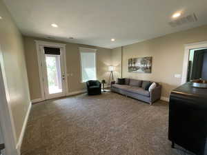 Carpeted living area with recessed lighting and baseboards