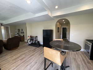 Dining area with arched walkways, light wood finished floors, and recessed lighting